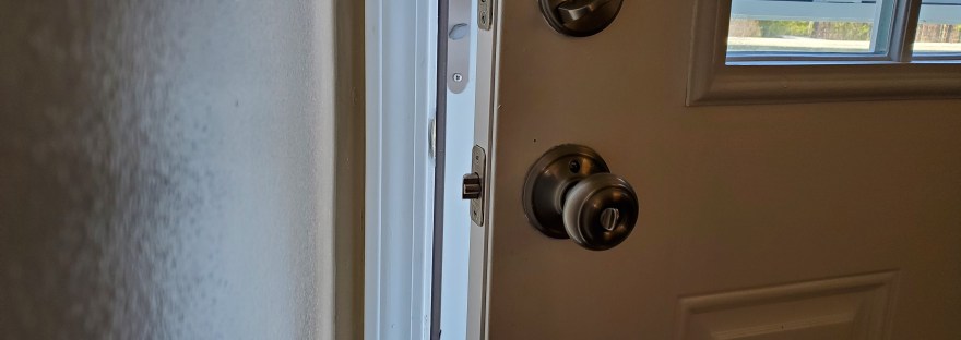 Daylight shines into a dim room through a partially open door.